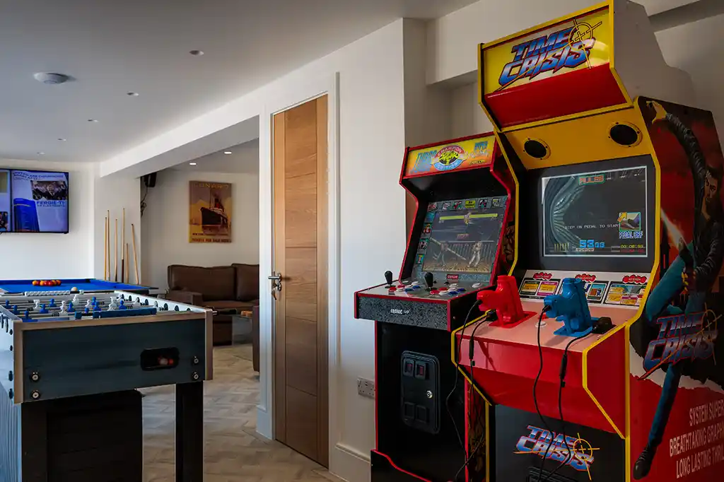Retro arcade machines, including Time Crisis, and a foosball table in the dedicated games room at Selsey Beach House.