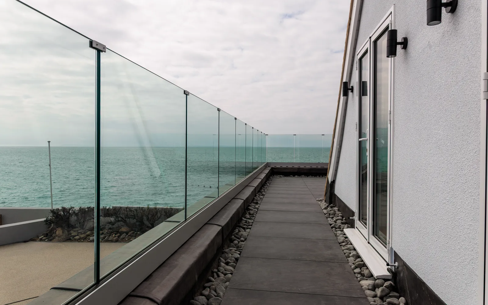 New first-floor terrace with glass balustrade and panoramic sea views at Selsey Beach House, designed by Jorges Salman Architects