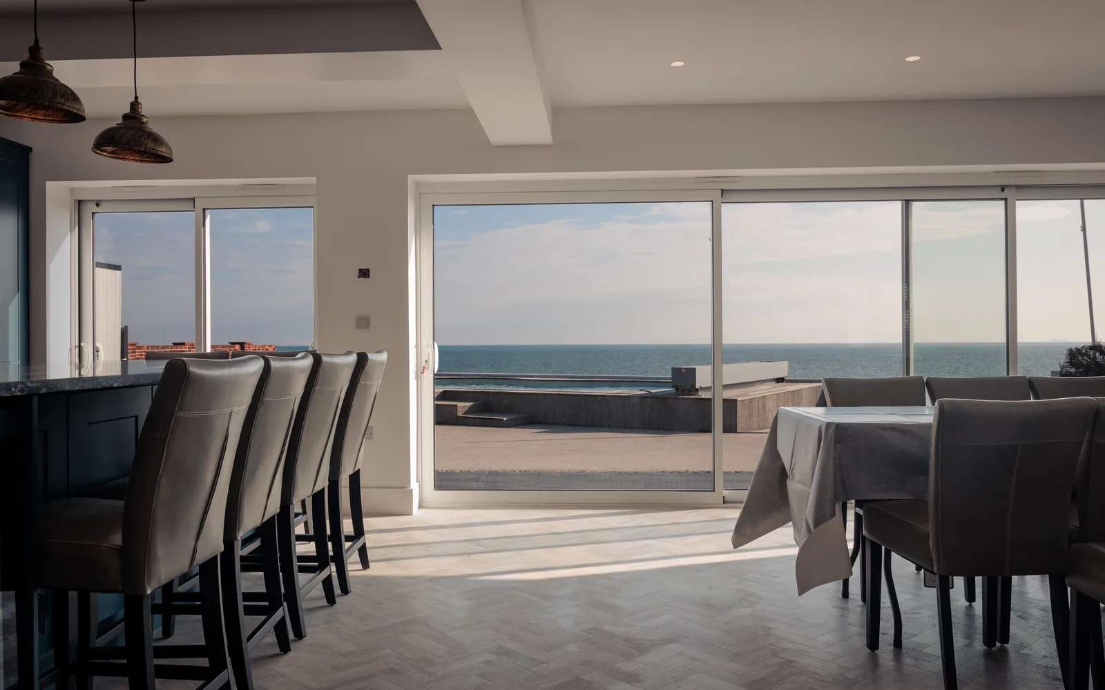 Open-plan kitchen and dining area in the new extension at Selsey Beach House, with sliding doors opening to sea views