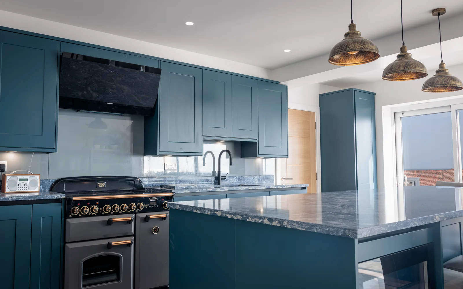 Newly renovated kitchen at Selsey Beach House with dark blue cabinetry, granite island and range cooker, built by Linkfern Ltd