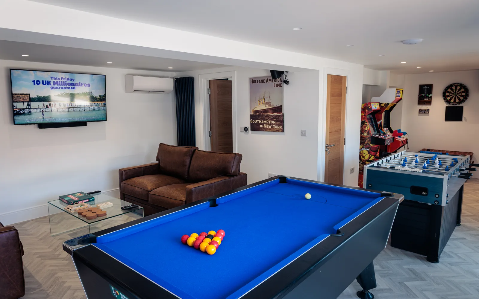 Expanded games room at Selsey Beach House with pool table, table football, darts and lounge seating